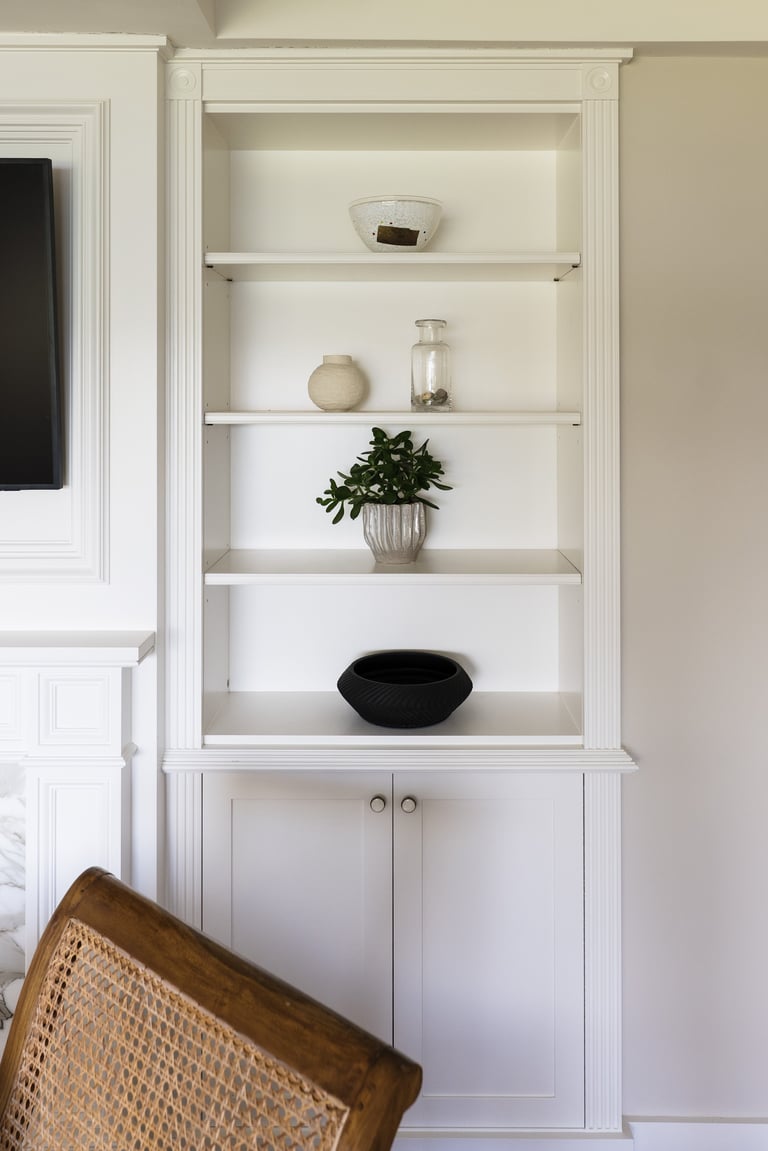 White built-in shelving unit with decorative items including plants, bowls, and containers, lower cabinet storage