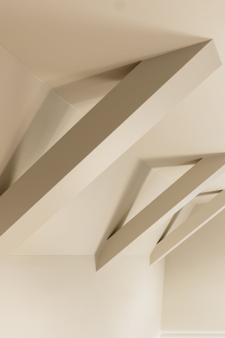 Abstract paper-cut art featuring layered beige and cream strips creating diagonal shadows and depth against a light background