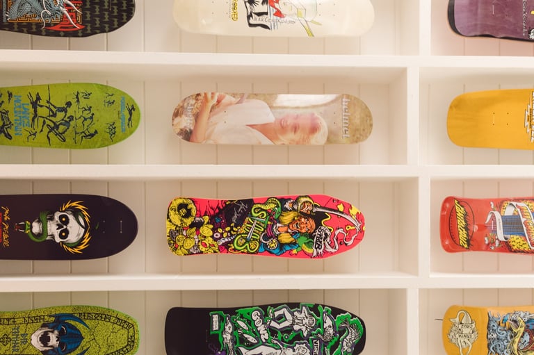 Collection of colorful skateboards displayed on white shelves with various artistic designs and graphics