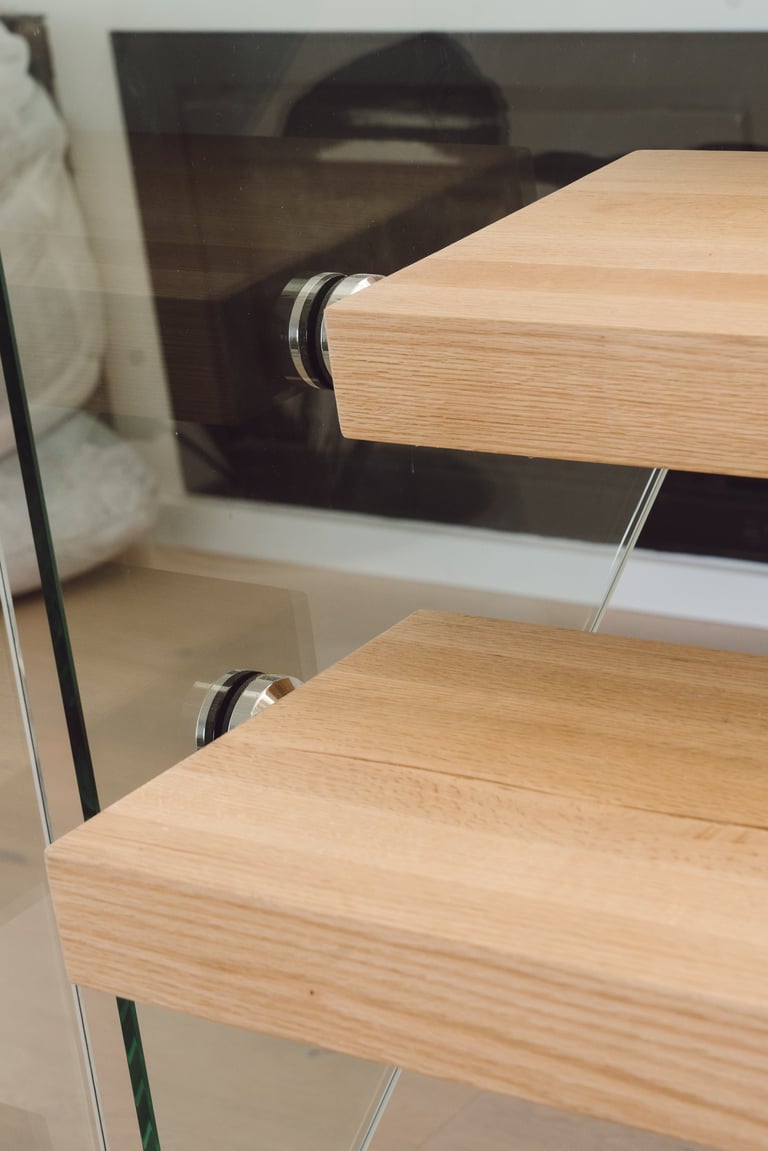 Wooden shelves with metal brackets mounted on a white wall inside a glass display cabinet