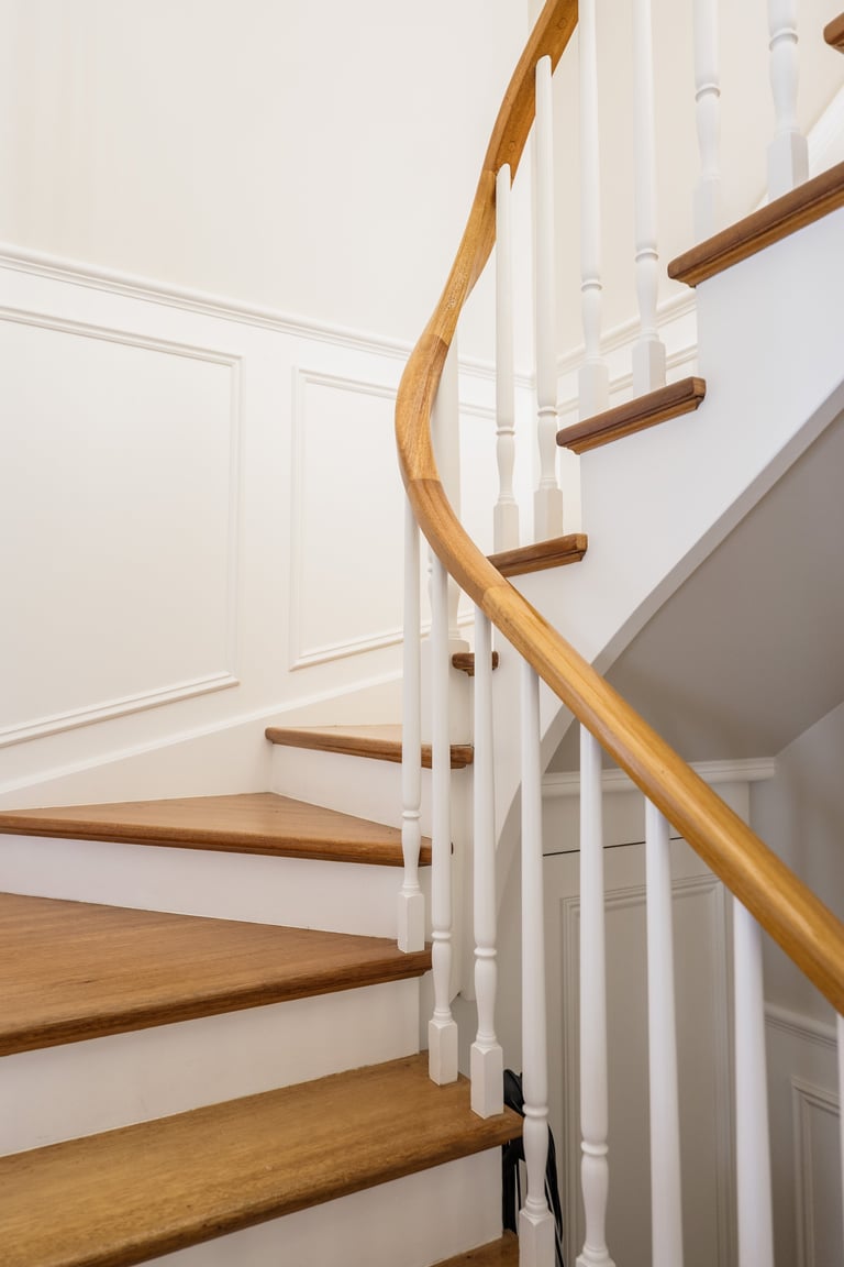 Modern staircase with wooden steps and curved handrail, white walls and spindles in a bright interior space