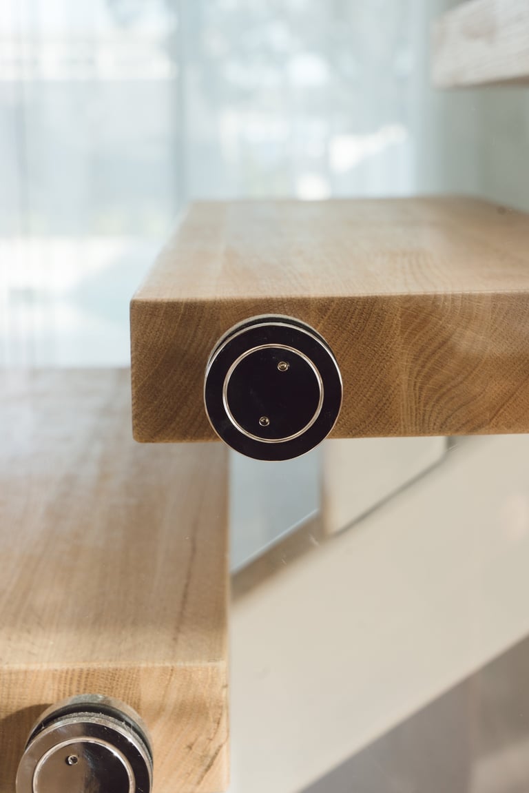 Close-up of a wooden desk with metal circular outlet sockets mounted on the edge, in a bright modern office