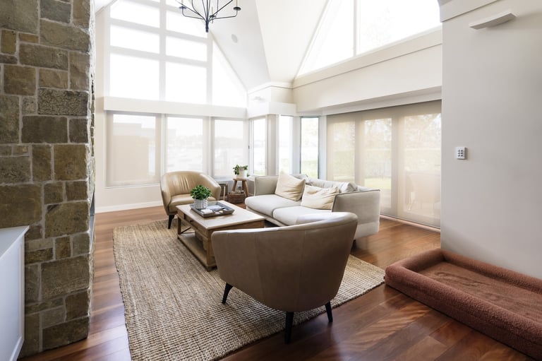 Modern living room with brown leather furniture, large windows, hardwood floors, and contemporary decor flooded with natural light