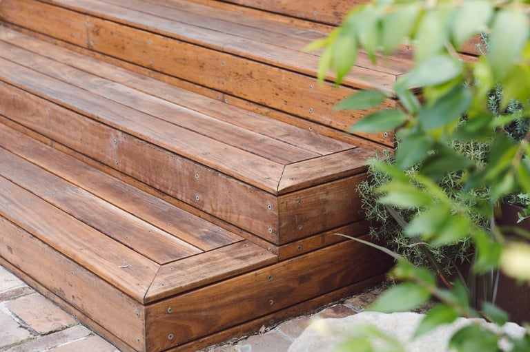 Close-up of wooden deck steps with green foliage in foreground