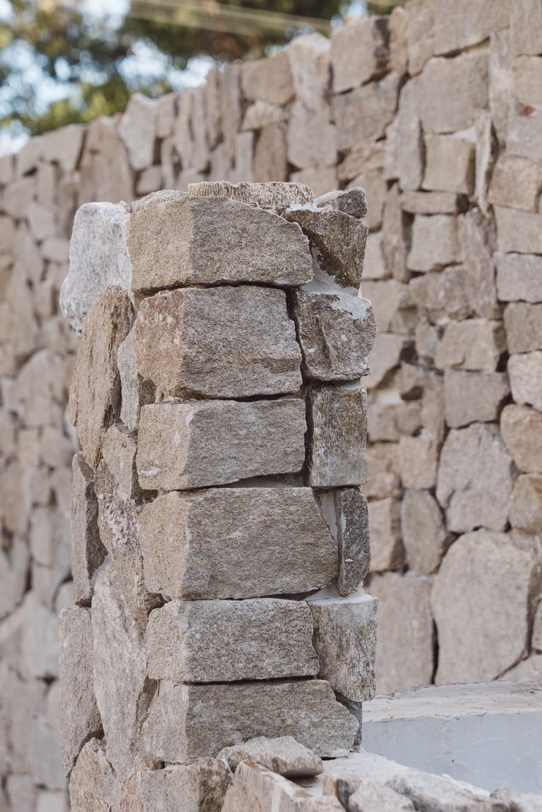 Stacked stone blocks forming a corner of an ancient adobe or stone wall structure with blurred background