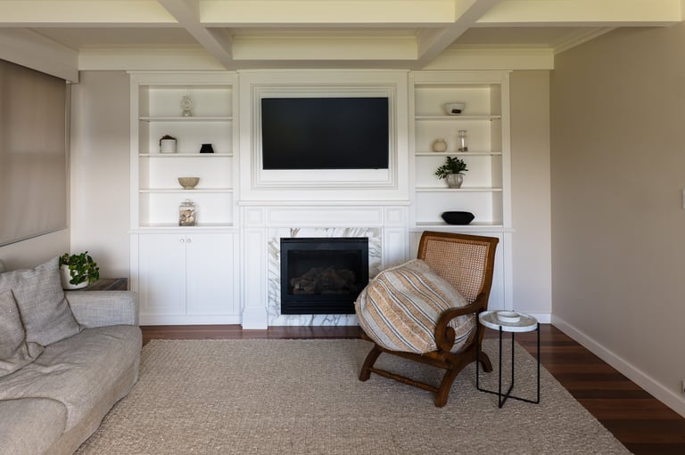 Modern living room with white built-in shelving, fireplace, mounted TV, comfortable seating, and wood flooring